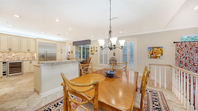 dining room featuring ornamental molding, beverage cooler, and an inviting chandelier