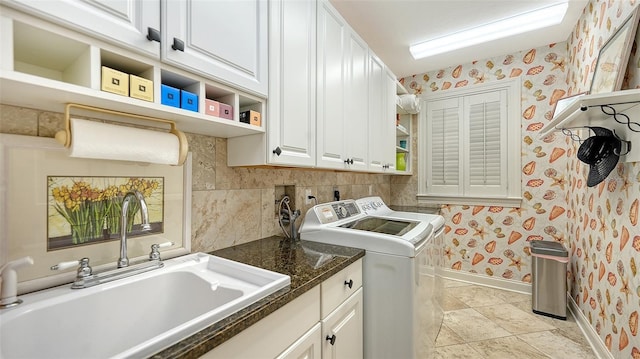 laundry area with washing machine and dryer, sink, light tile patterned floors, and cabinets