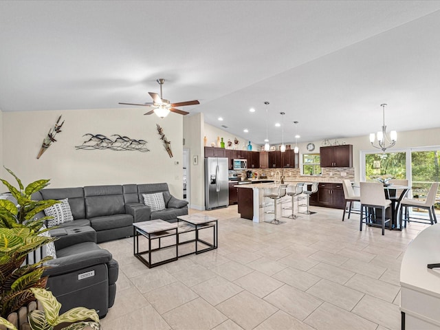 living room featuring light tile patterned floors, ceiling fan with notable chandelier, and lofted ceiling