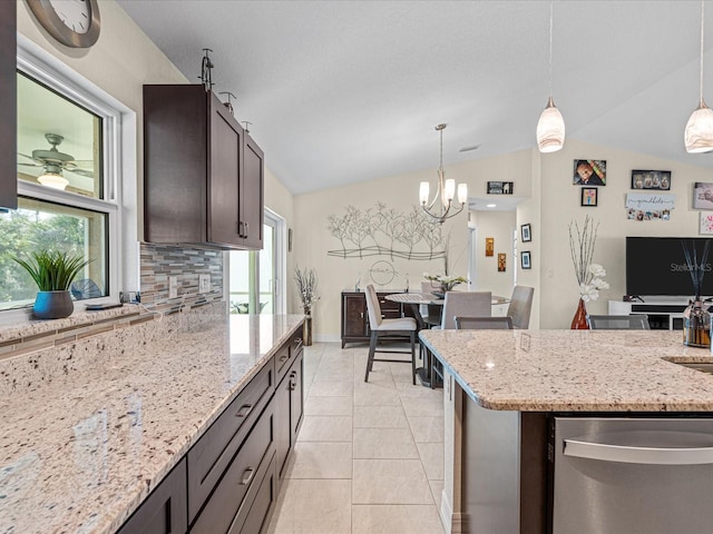 kitchen with light stone countertops, decorative backsplash, stainless steel dishwasher, pendant lighting, and lofted ceiling