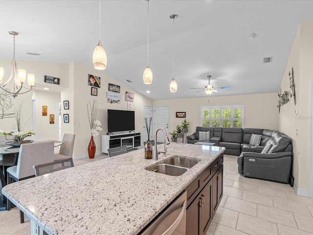 kitchen featuring pendant lighting, lofted ceiling, ceiling fan with notable chandelier, sink, and light stone countertops