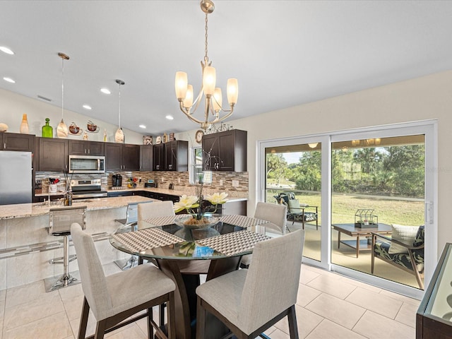 dining area featuring plenty of natural light, light tile patterned floors, lofted ceiling, and an inviting chandelier