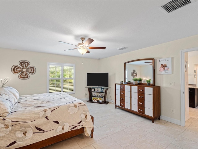 bedroom featuring light tile patterned floors, a textured ceiling, ensuite bathroom, and ceiling fan