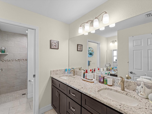 bathroom featuring tile patterned flooring, vanity, and a tile shower