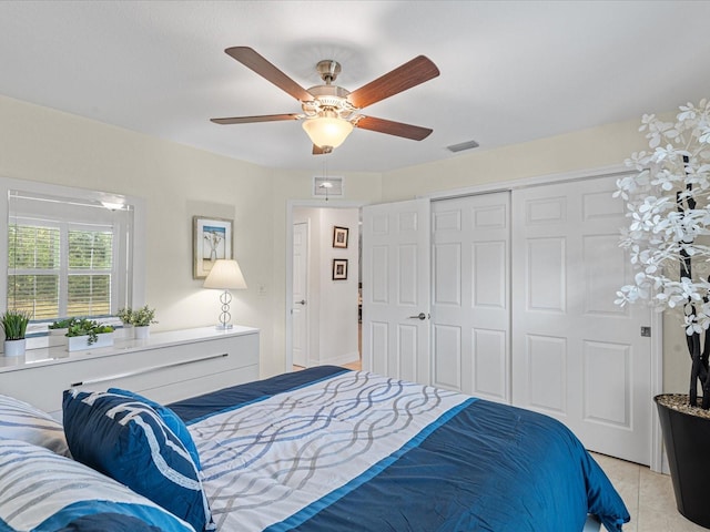 tiled bedroom with ceiling fan and a closet