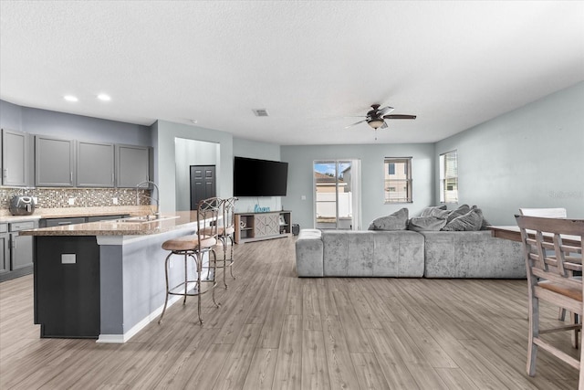 living room with light hardwood / wood-style floors, sink, and a textured ceiling