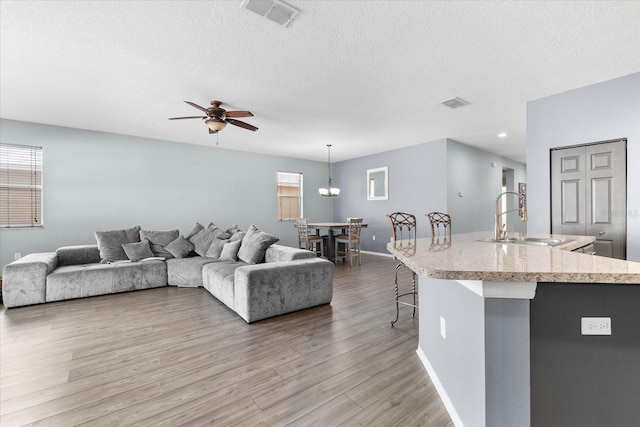 living room featuring sink, a textured ceiling, ceiling fan, and light hardwood / wood-style flooring