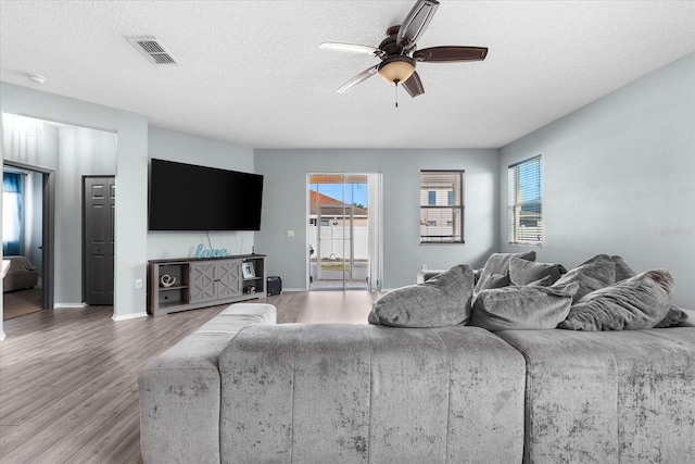 living room featuring hardwood / wood-style floors, a wealth of natural light, a textured ceiling, and ceiling fan