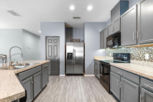 kitchen featuring tasteful backsplash, gray cabinetry, sink, and black appliances