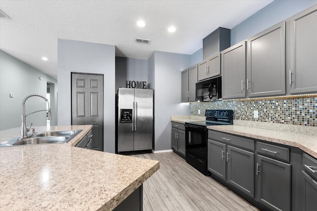 kitchen featuring sink, gray cabinetry, backsplash, black appliances, and light wood-type flooring