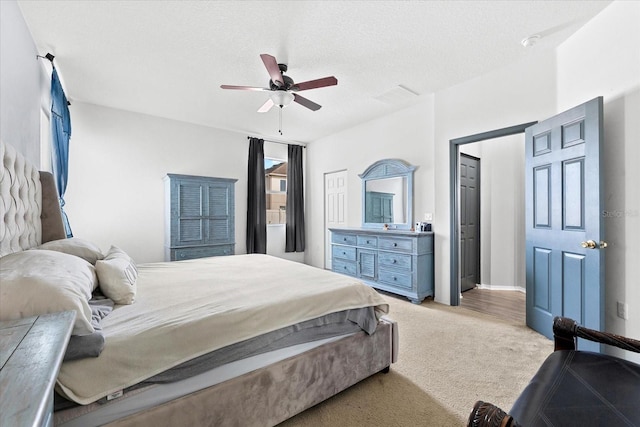 bedroom with a textured ceiling, light colored carpet, and ceiling fan