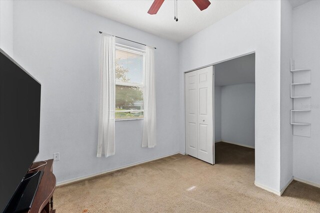 unfurnished bedroom featuring light colored carpet, a closet, and ceiling fan