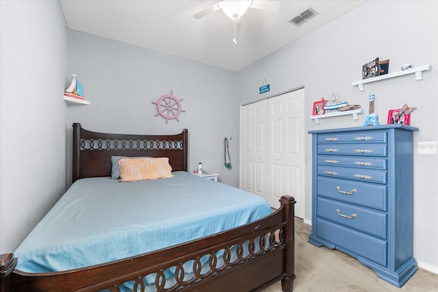 bedroom with ceiling fan, light carpet, and a closet