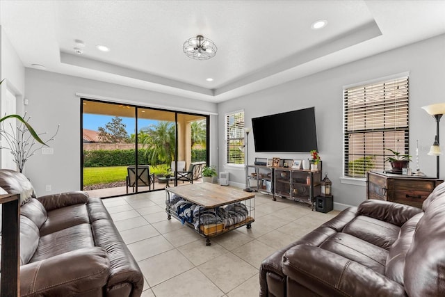 living room with light tile patterned flooring and a tray ceiling