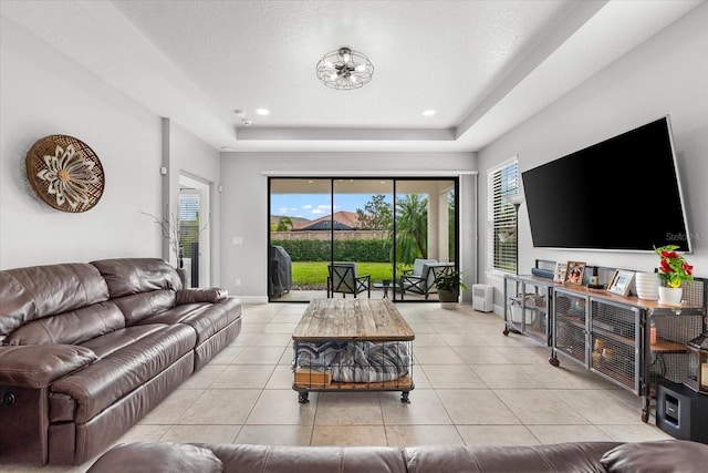 living room with a textured ceiling, light tile patterned floors, and a raised ceiling