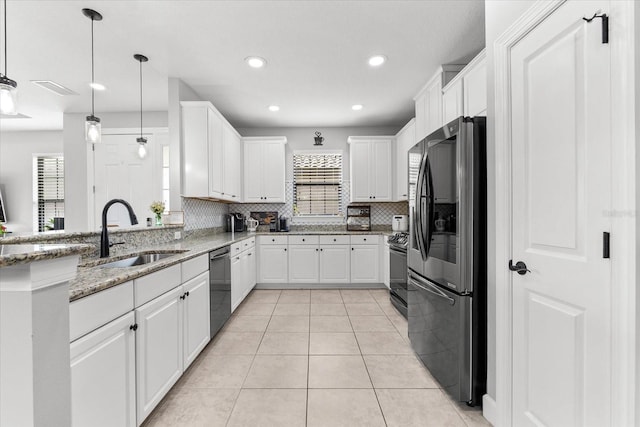 kitchen featuring light stone countertops, white cabinets, appliances with stainless steel finishes, sink, and hanging light fixtures