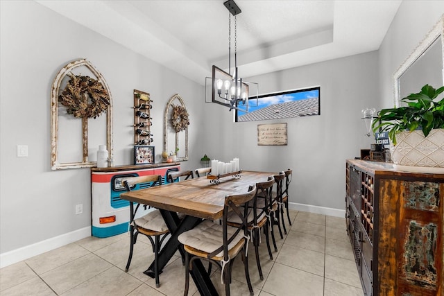 tiled dining space featuring an inviting chandelier and a tray ceiling