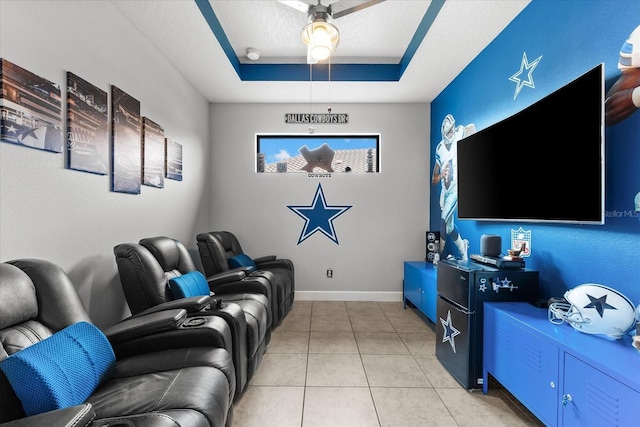 home theater room with a tray ceiling and light tile patterned flooring