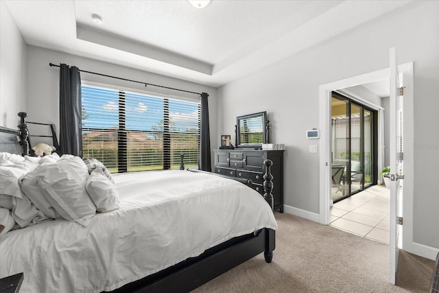 bedroom featuring access to exterior, a tray ceiling, and multiple windows