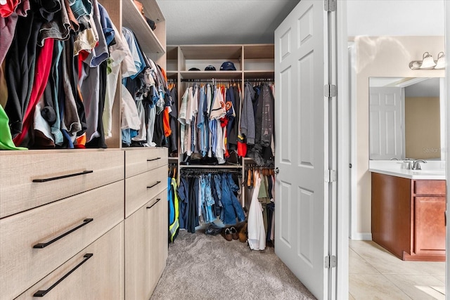 walk in closet with sink and light carpet