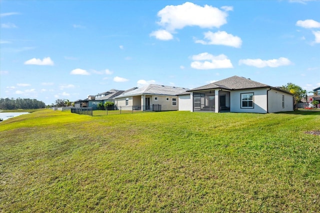 back of house with a yard, a sunroom, and a water view