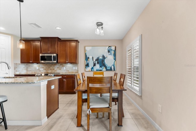 kitchen with light stone counters, sink, decorative light fixtures, and light tile patterned floors