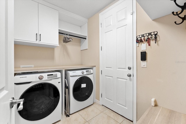 washroom featuring cabinets, washer and dryer, and light tile patterned floors