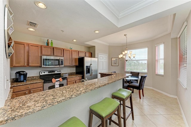 kitchen featuring a chandelier, a kitchen bar, stainless steel appliances, and crown molding