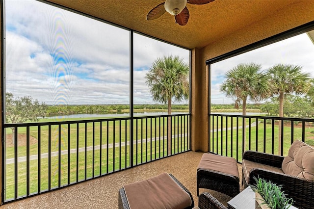 sunroom / solarium featuring ceiling fan and a water view