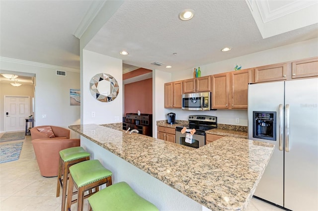 kitchen with stainless steel appliances, light stone counters, kitchen peninsula, crown molding, and a kitchen bar