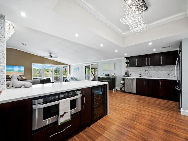 kitchen with backsplash, stainless steel dishwasher, dark brown cabinets, ceiling fan with notable chandelier, and light hardwood / wood-style flooring