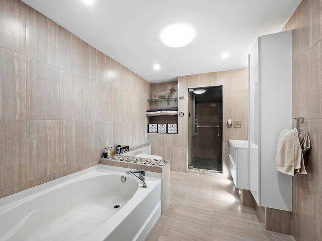 bathroom with independent shower and bath, vanity, tile walls, and tile patterned floors