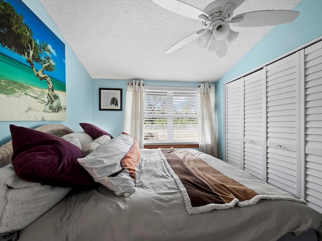 bedroom featuring ceiling fan, lofted ceiling, a closet, and a textured ceiling