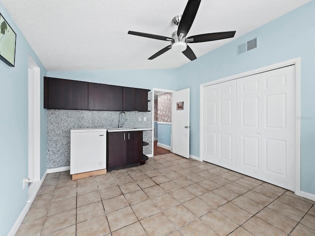 kitchen featuring dark brown cabinetry, sink, tasteful backsplash, vaulted ceiling, and light tile patterned floors