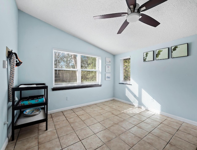 tiled spare room featuring a textured ceiling, ceiling fan, and lofted ceiling