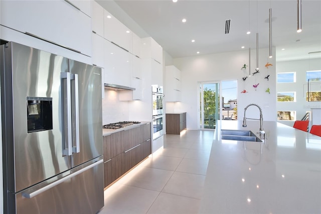 kitchen with light tile patterned floors, white cabinets, modern cabinets, stainless steel appliances, and a sink