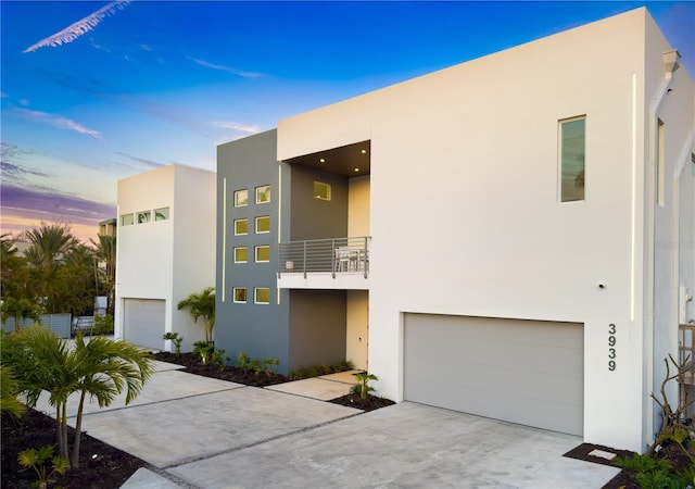 view of front of home with a garage, concrete driveway, a balcony, and stucco siding