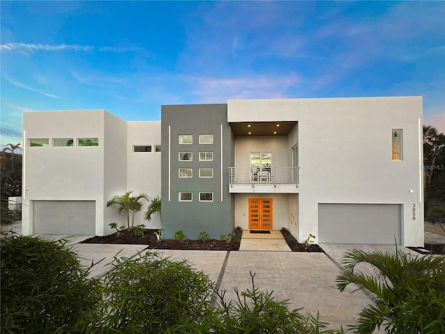 view of front of home with a balcony, an attached garage, and stucco siding