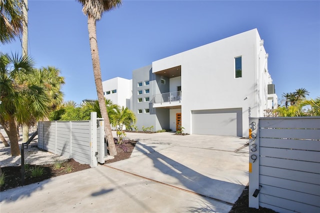 contemporary house featuring driveway, a garage, fence, and stucco siding