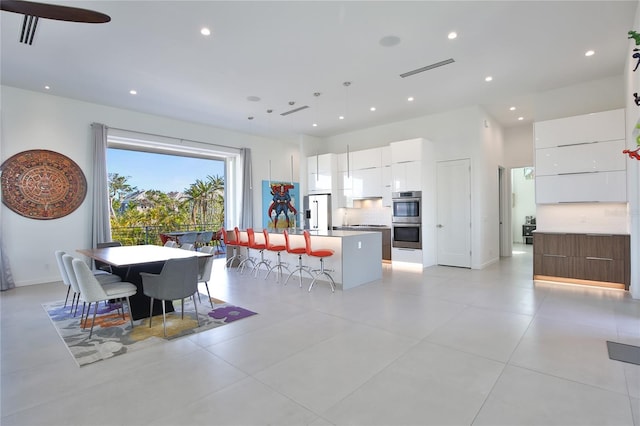 dining space featuring a towering ceiling, baseboards, visible vents, and recessed lighting