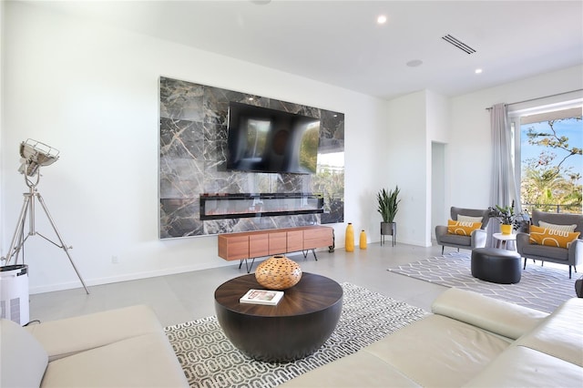 living area with visible vents, baseboards, a high end fireplace, finished concrete floors, and recessed lighting