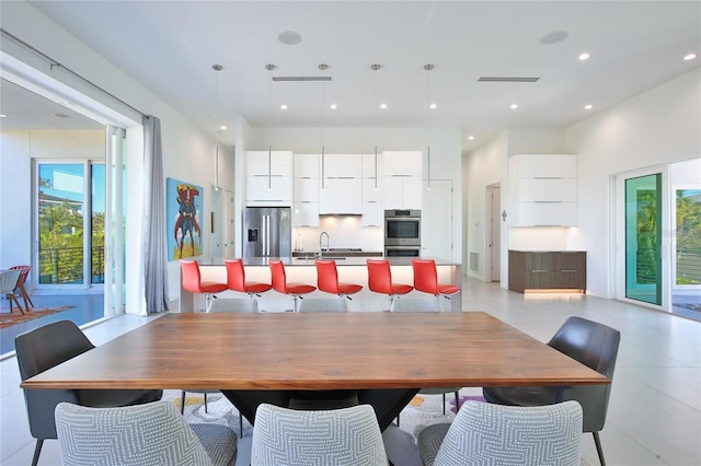 dining area with recessed lighting, a healthy amount of sunlight, visible vents, and a towering ceiling