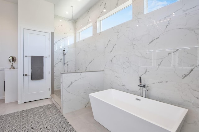 full bath with a freestanding bath, stone wall, and a marble finish shower