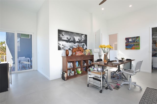 dining room with finished concrete floors, a high ceiling, baseboards, and recessed lighting