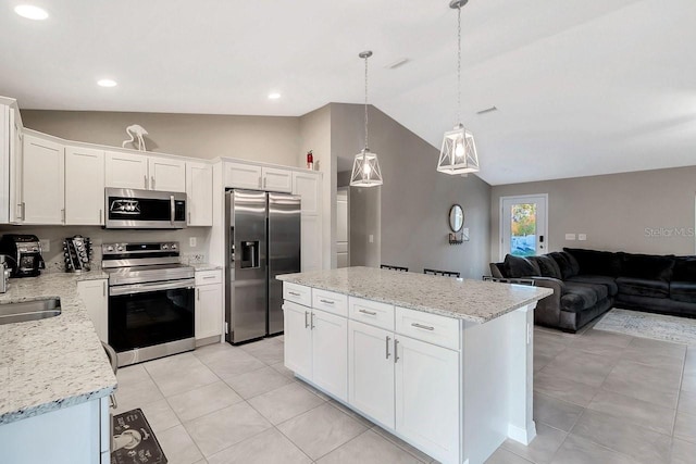 kitchen with lofted ceiling, stainless steel appliances, white cabinets, a kitchen island, and decorative light fixtures