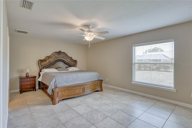 tiled bedroom featuring ceiling fan and a textured ceiling