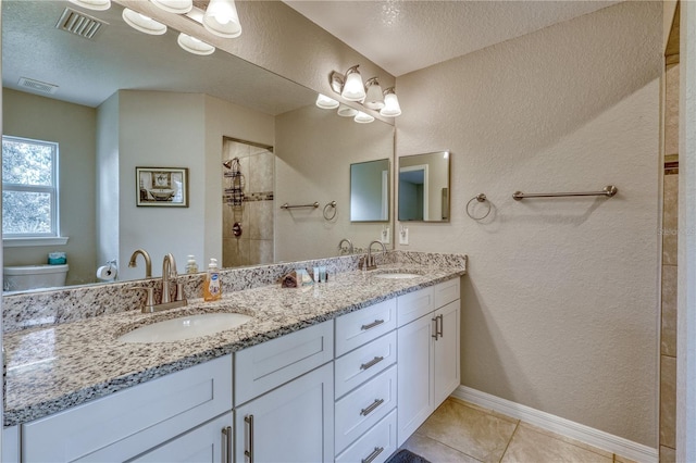 bathroom featuring tiled shower, tile patterned floors, toilet, a textured ceiling, and vanity