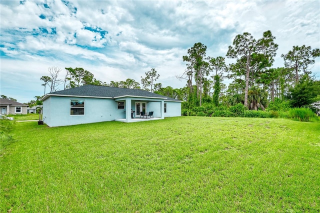 back of property with a lawn and a patio