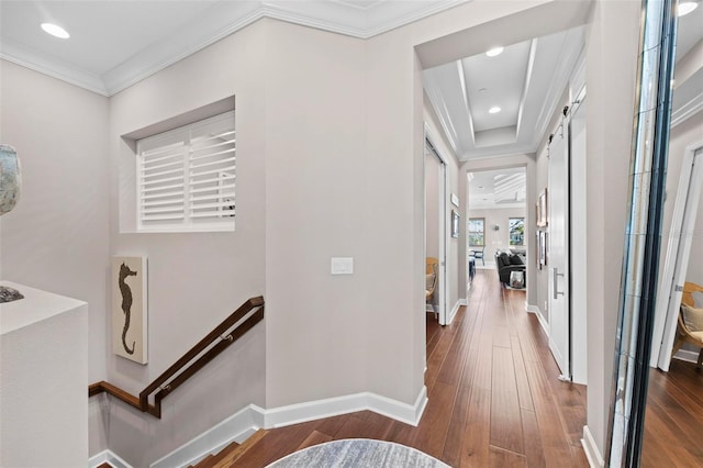 hall featuring a barn door, crown molding, and hardwood / wood-style flooring