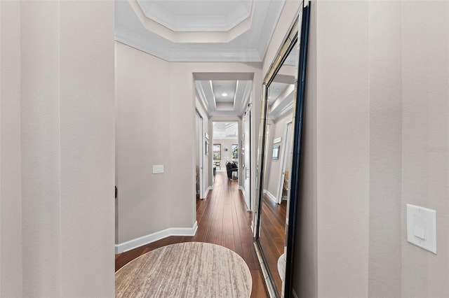 hall featuring ornamental molding, dark wood-type flooring, and a tray ceiling